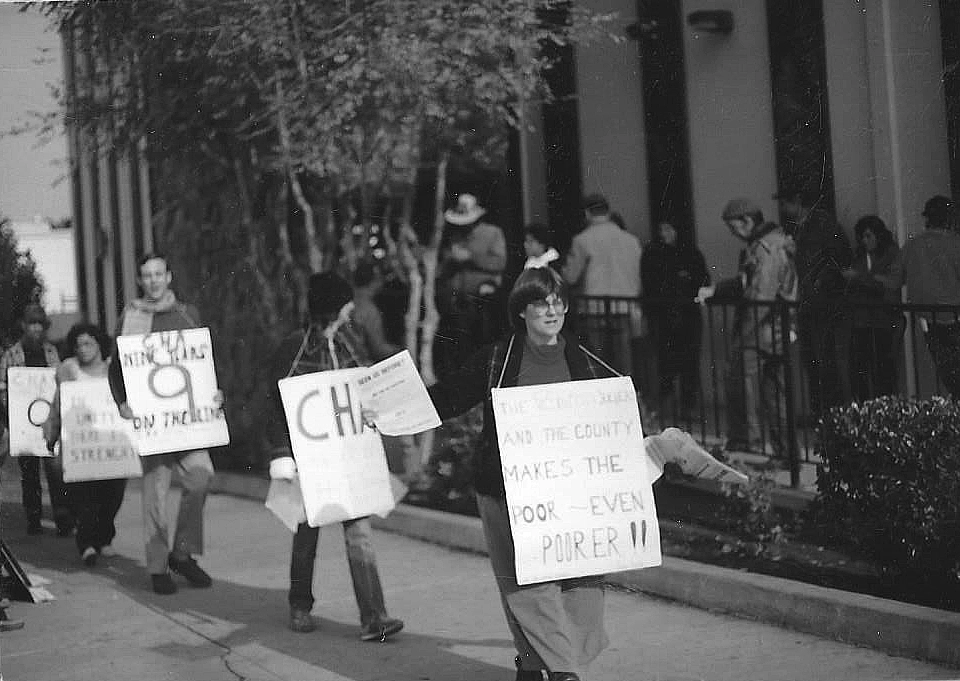 Black and white photo of picketers holding signs and marching.