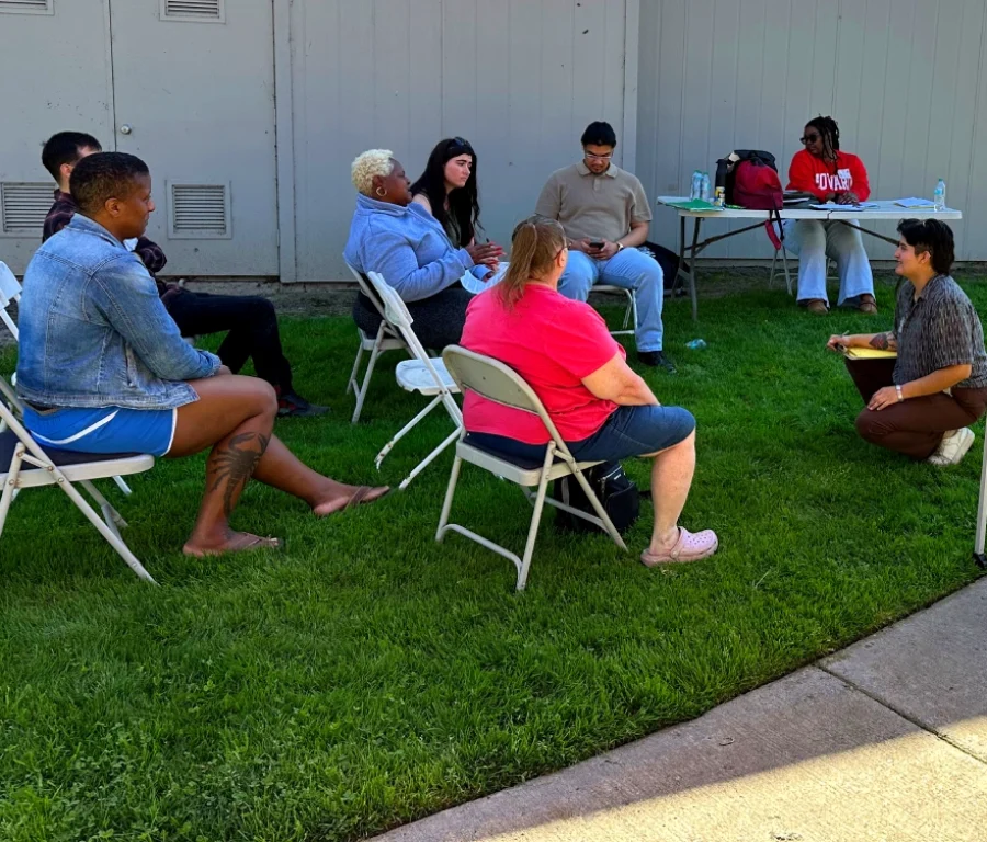group of people sitting outdoors in a meeting.